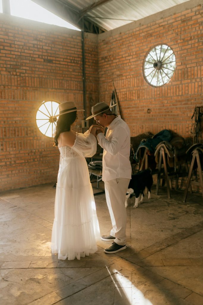 couple-in-hats-in-a-rustic-barn-with-sunlight-hzk-r54cvew