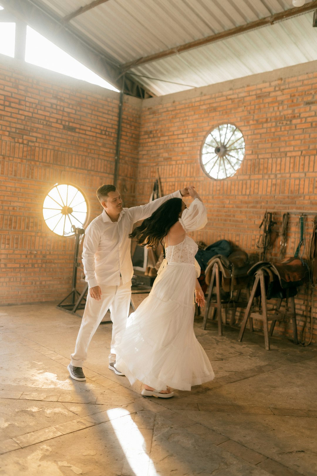 couple-in-white-dancing-in-a-rustic-barn-svmvggvkpus